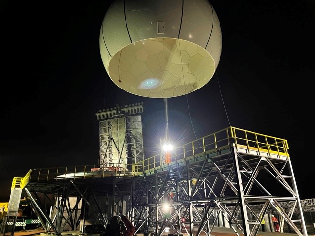 Image of radome being lifted into position at night