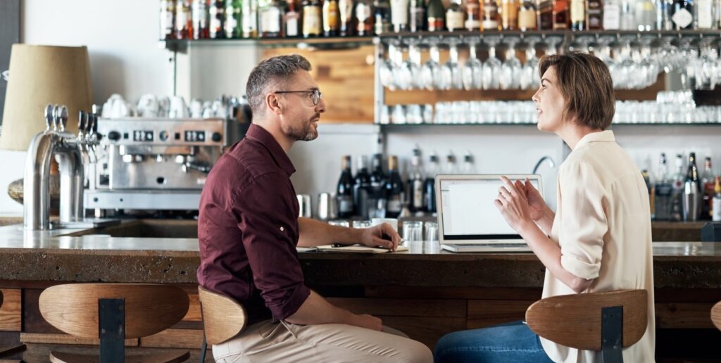 Cropped shot of two people talking in a cafe.