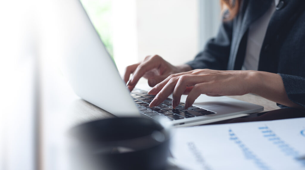 Businesswoman working on a laptop with paperwork on the desk