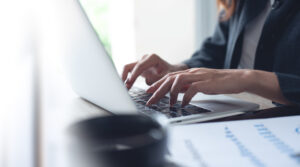 Businesswoman working on a laptop with paperwork on the desk